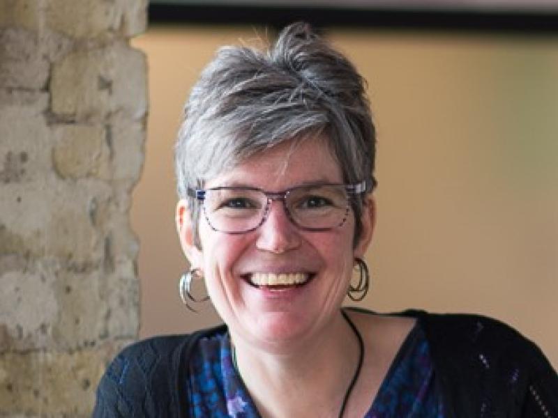 woman leaning against a half wall smiling